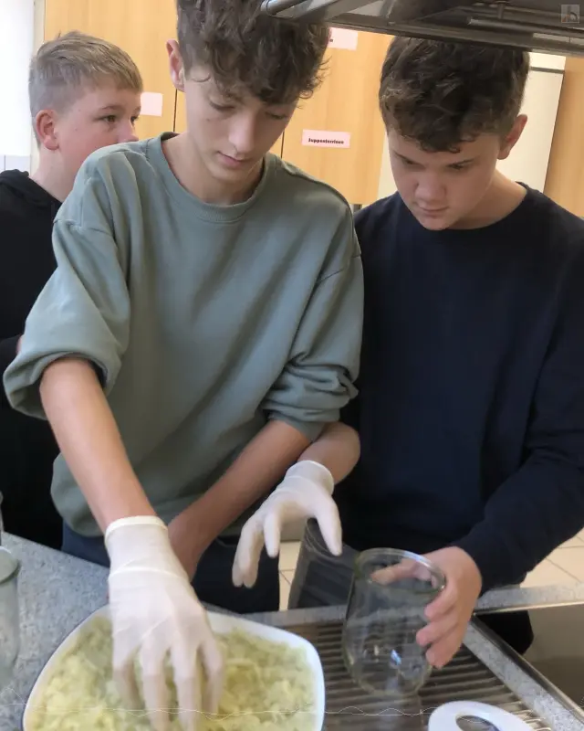 Zwei Jungs befllen Einmachglser mit Kraut