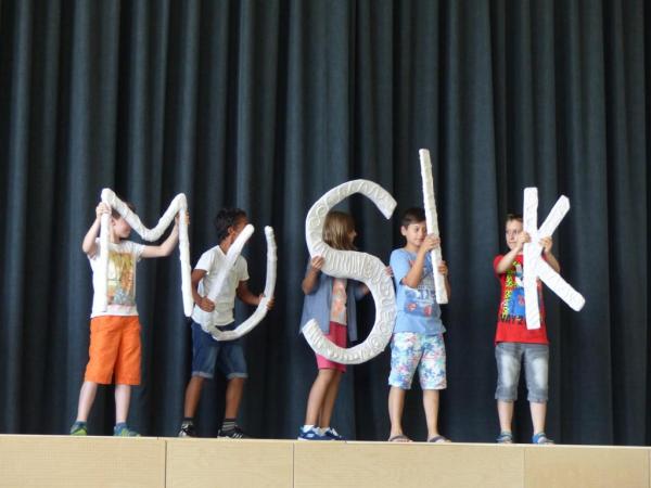 Aufführung: Schüler halten die Buchstaben des Wortes "Musik" hoch.