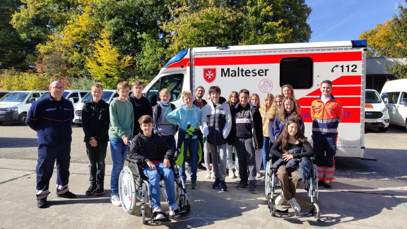 Schülergruppe vor Rettungswagen der Malteser.